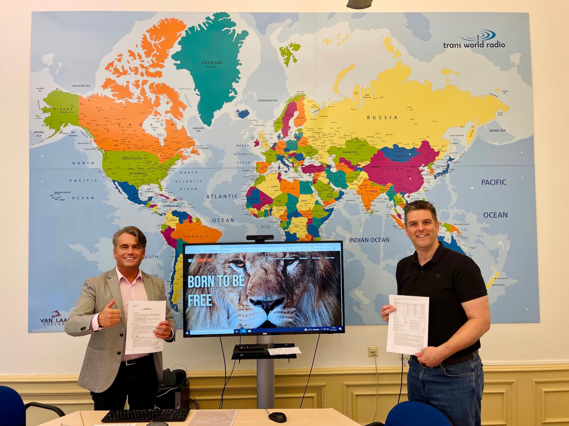 Ondertekening van de samenwerking met Trans World Radio, bij de wereldkaart van TWR